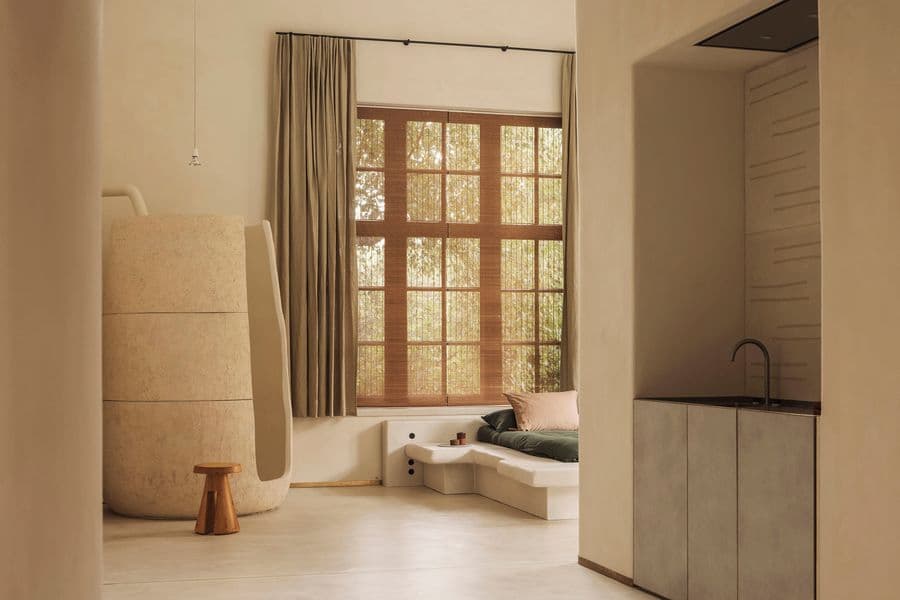 A sculptural bedroom connects a curved built-in bed with a rounded architectural form and compact kitchen
