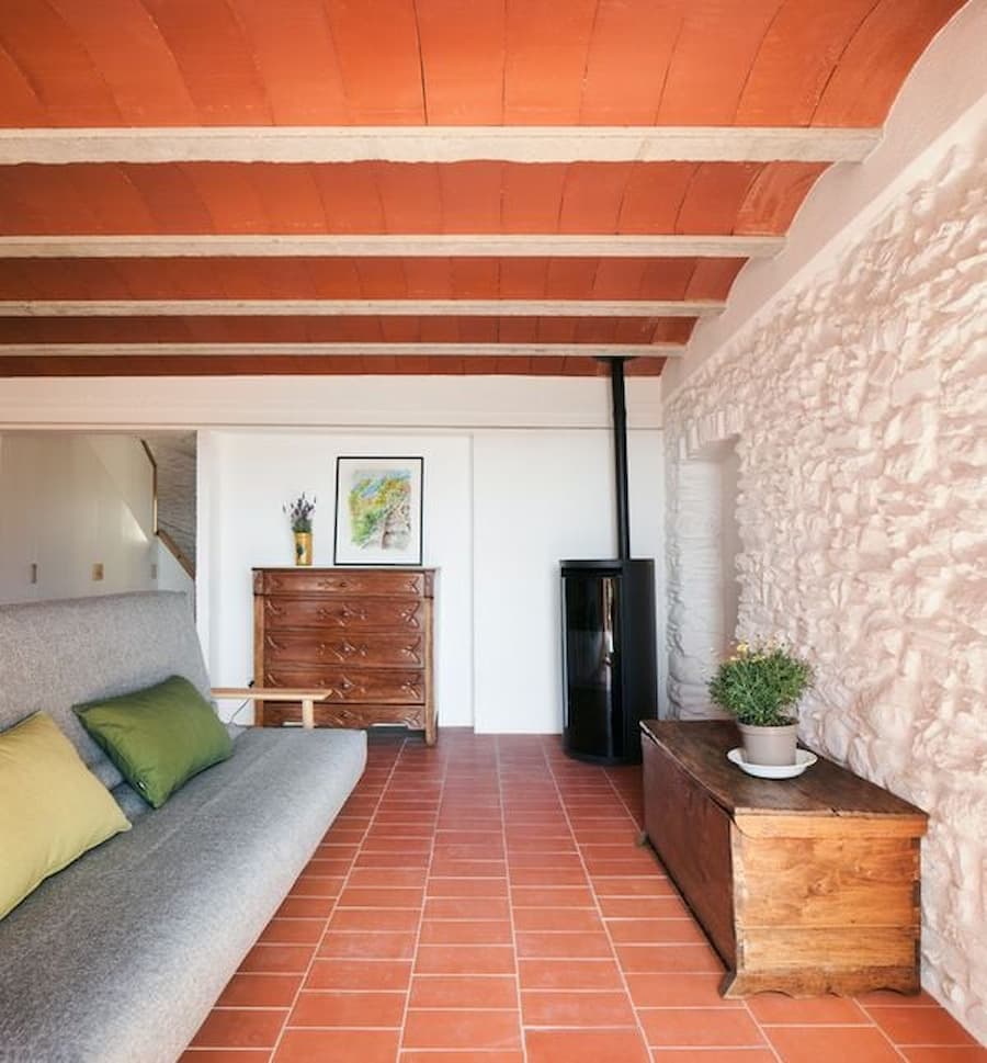 Living room with restored stone wall and Catalan vaulted ceiling at Ca la Carolina.