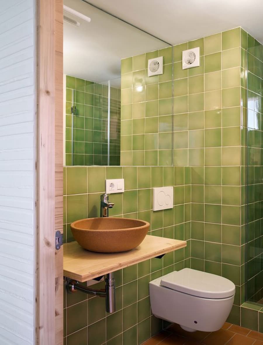 Green ceramic tile bathroom with handcrafted basin inside Ca la Carolina rural house renovation.