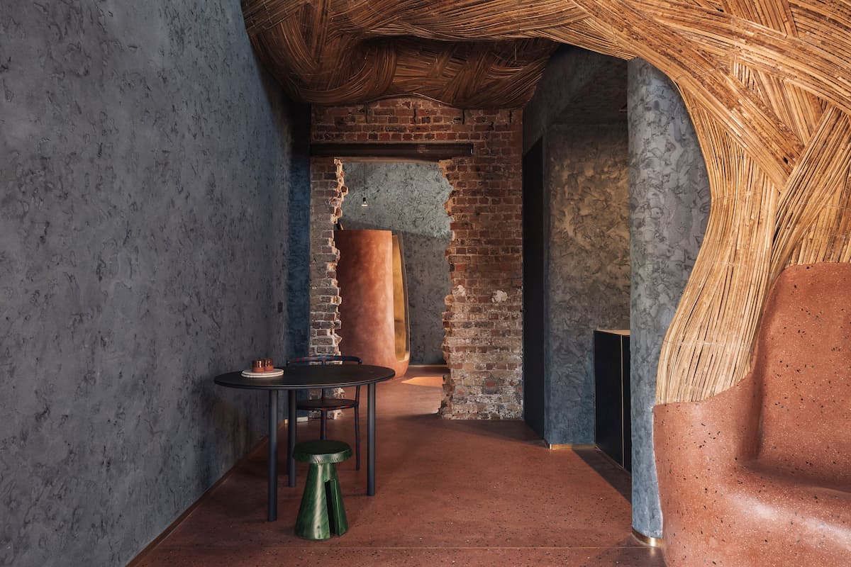 Jonojé interior with textured plaster walls, exposed brick, clay furniture and woven bamboo ceiling by Studio LOHO.