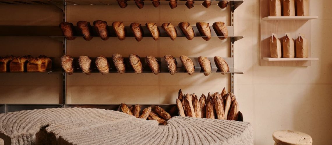 bakery interior with wooden shelves and rows of artisan bread in warm natural light