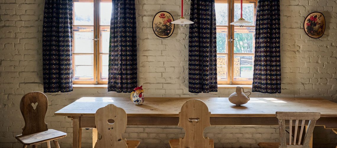 Traditional Bavarian farmhouse interior with wooden furniture, brick walls, and natural daylight from twin windows