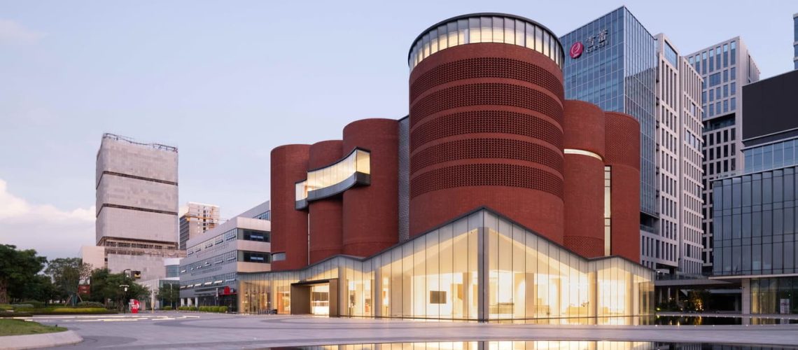 紅磚圓柱與玻璃基座構成的建築外觀與水面倒影 廣州雪蕾香氛博物館