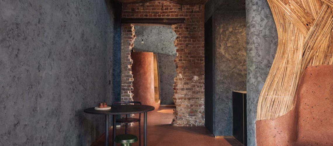 Jonojé interior with textured plaster walls, exposed brick, clay furniture and woven bamboo ceiling by Studio LOHO.